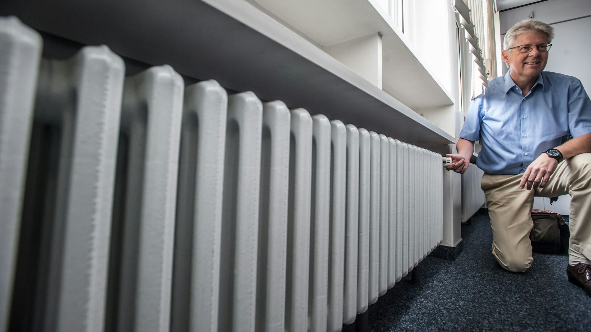 Der frühere WGL-Geschäftsführer Wolfgang Mues hockt vor einem Heizkörper.