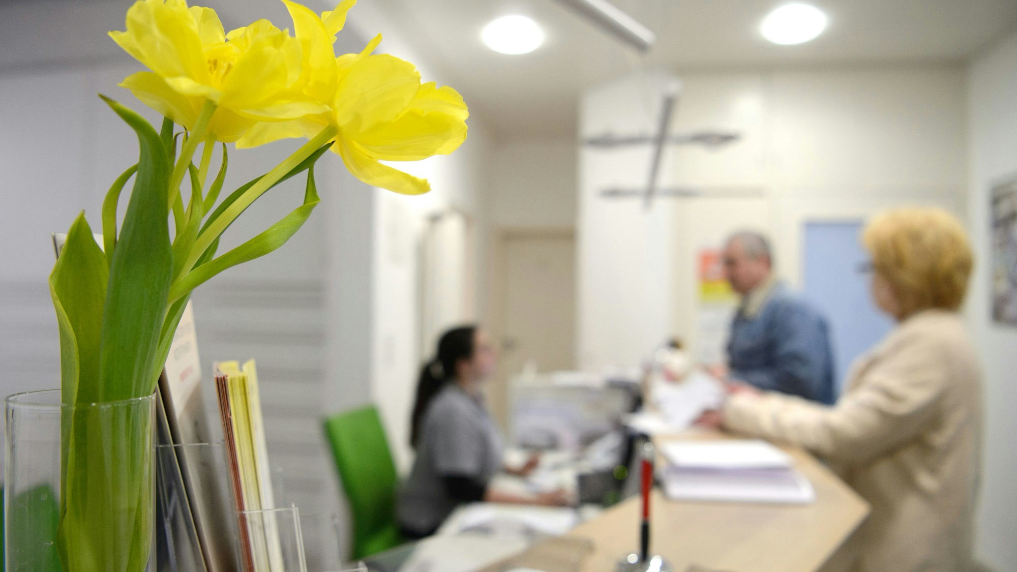Blumen stehen am Empfang einer Arztpraxis.