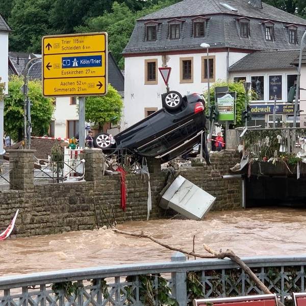 Am Morgen des 15. Juli 2021 zeigt sich das Ausmaß der Flutkatastrophe. In Gemünd hängt ein schwarzer SUV kopfüber auf dem Geländer an der Olef.