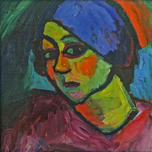 Eine Frau mit grüner Haut, roten Wangen und blauem Turban schaut den Betrachter an.