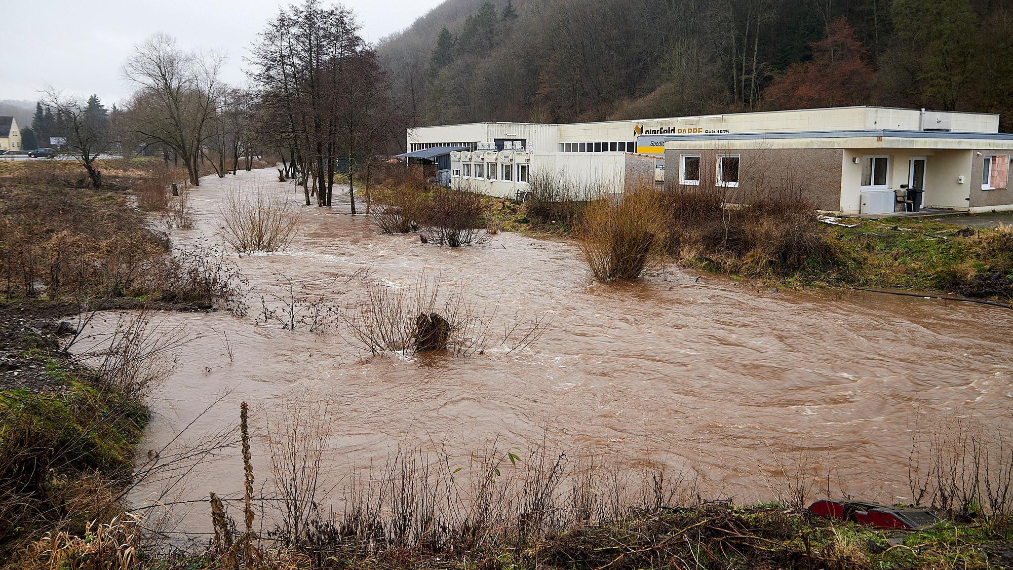 Das Bild zeigt die Hochwasser führende Olef, rechts die Pappenfabrik.