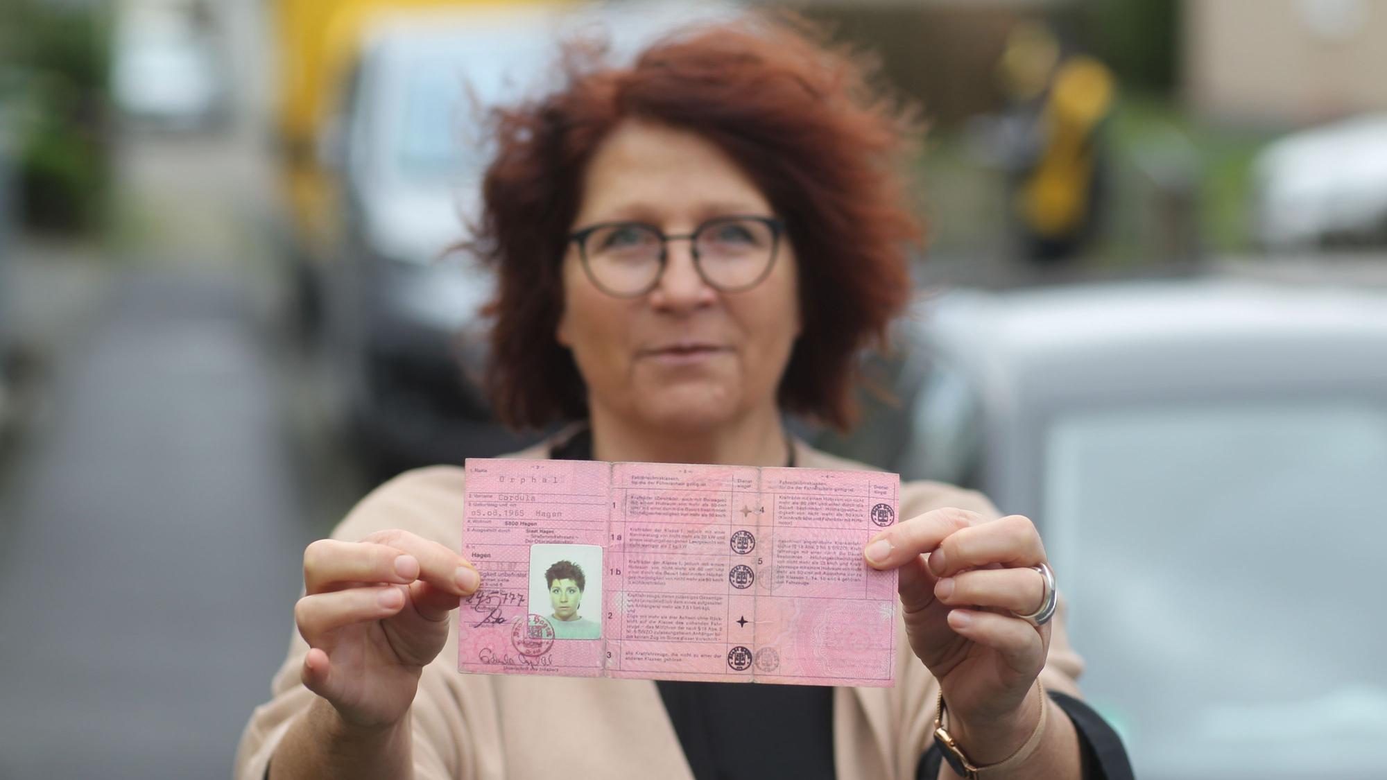 Eine Frau hält ihren alten Führerschein in die Kamera.