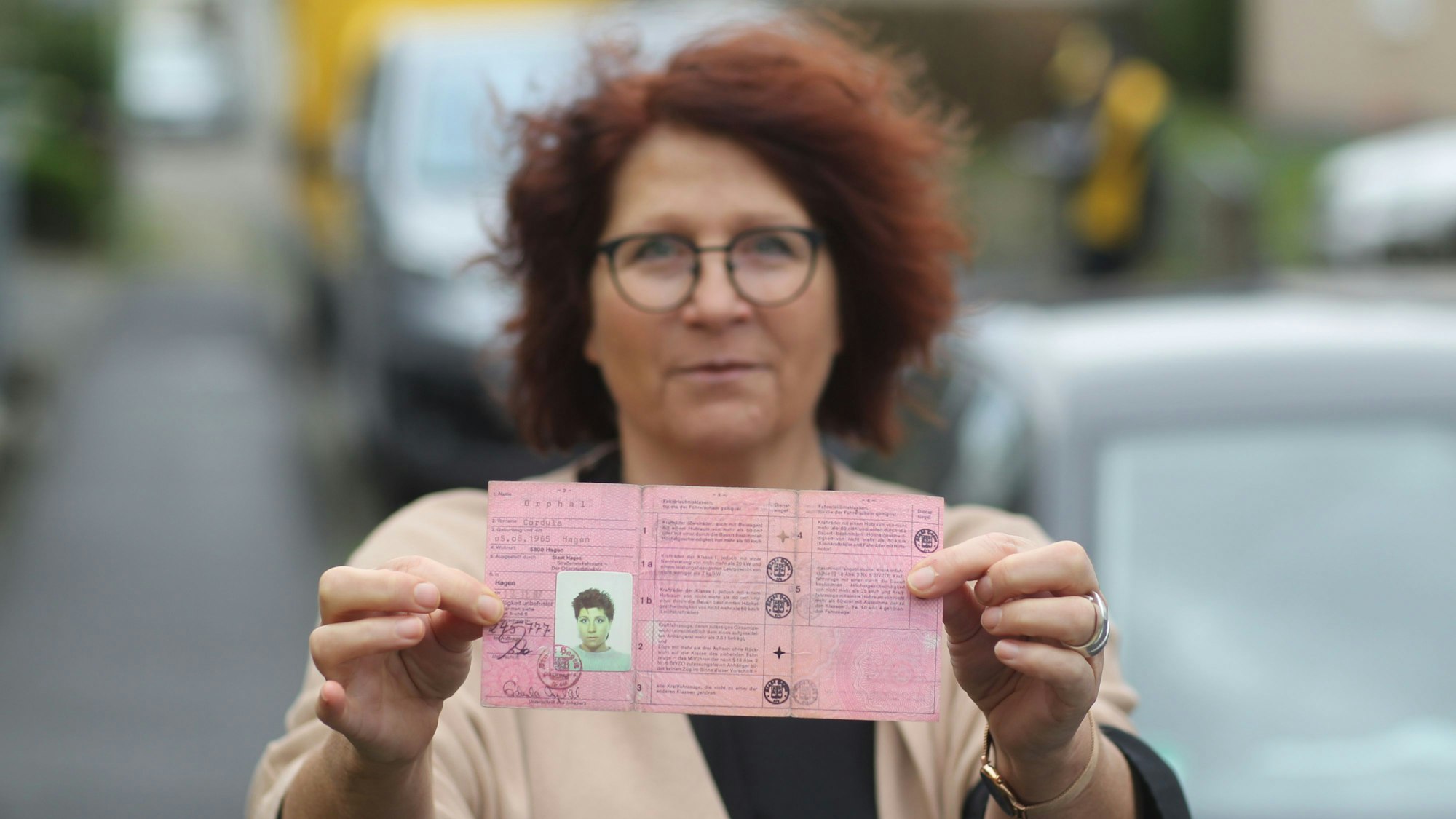 Eine Frau hält ihren alten Führerschein in die Kamera.