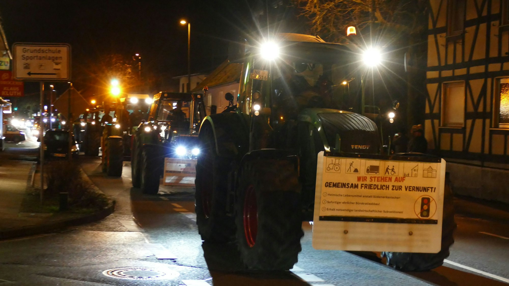 Ein Protestzug aus Traktoren fährt über eine Straße.
