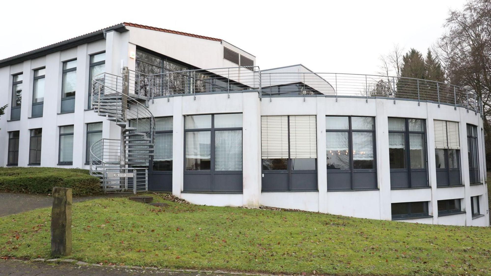 Ein weißes Gebäude, zum Teil in Bogenform gebaut, mit großen Fensterflächen