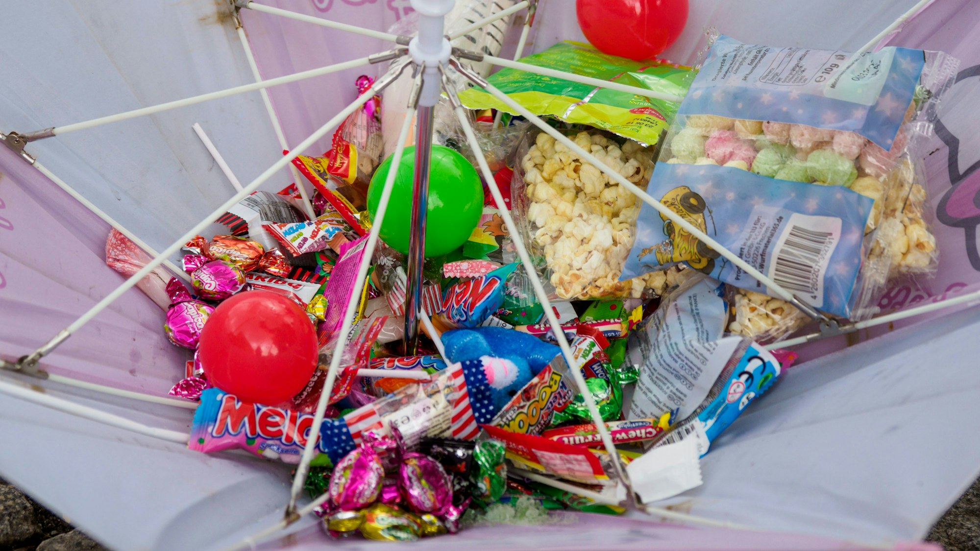 Mit vollen Händen wird Kamelle geworfen bei einem Rosensonntagsumzug.