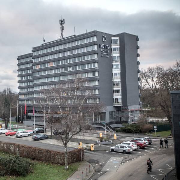 Das Delta Hotel by Marriott in Wiesdorf von außen. Vor dem Gebäude stehen Autos. Links im Hintergrund ist der Wasserturm zu sehen.