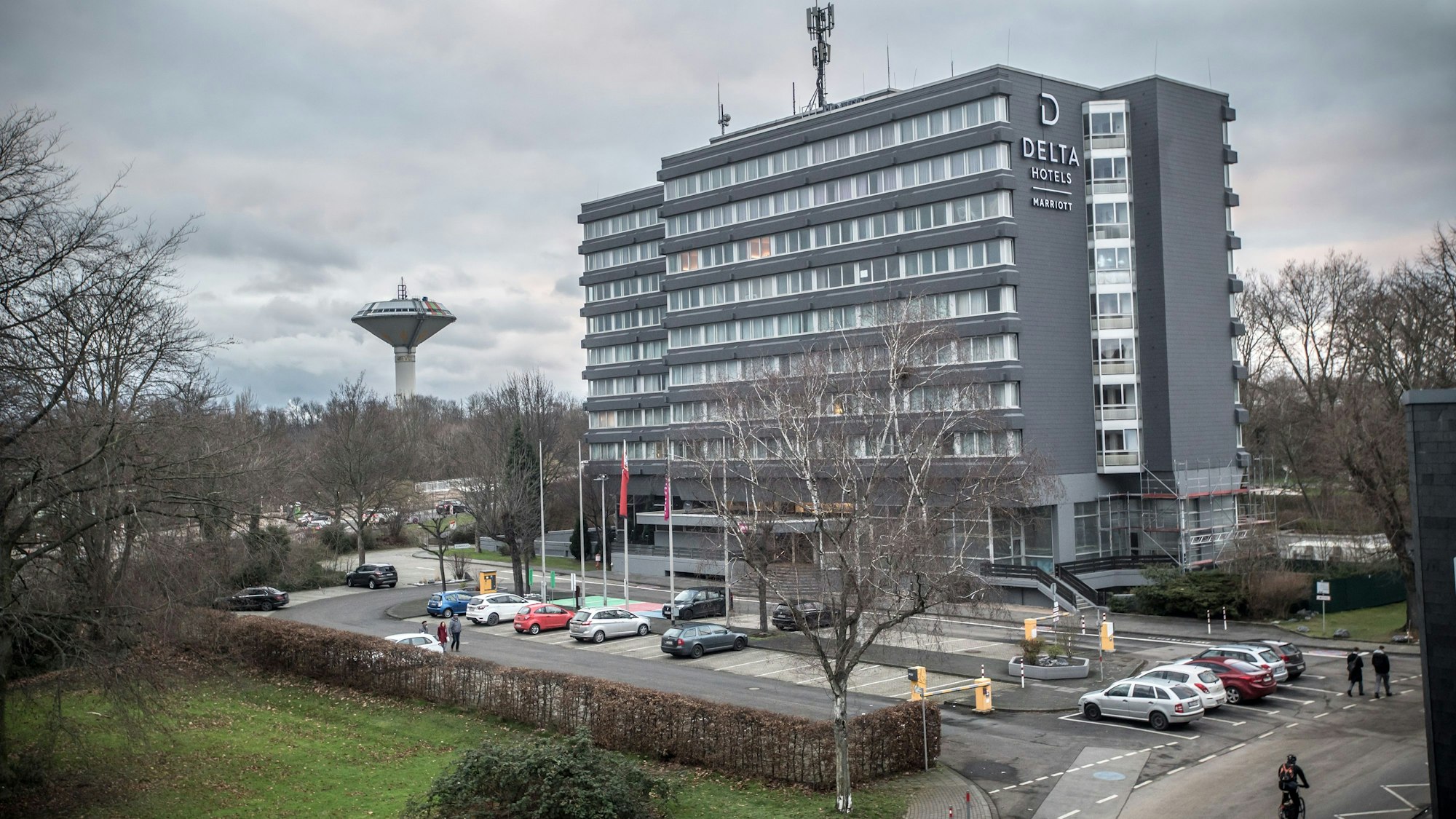 Das Delta Hotel by Marriott in Wiesdorf von außen. Vor dem Gebäude stehen Autos. Links im Hintergrund ist der Wasserturm zu sehen.