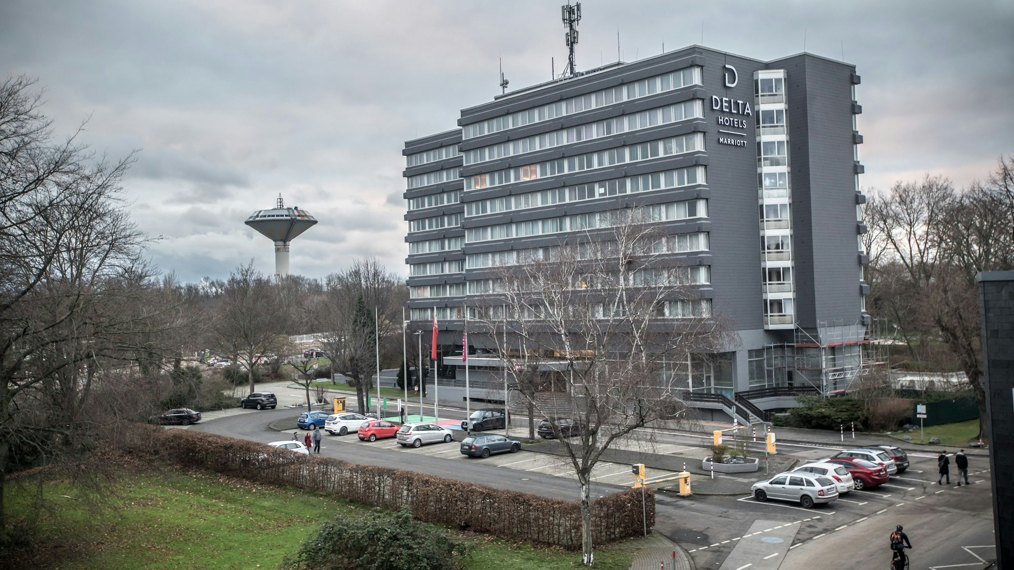 Das Delta Hotel by Marriott in Wiesdorf von außen. Vor dem Gebäude stehen Autos. Links im Hintergrund ist der Wasserturm zu sehen.