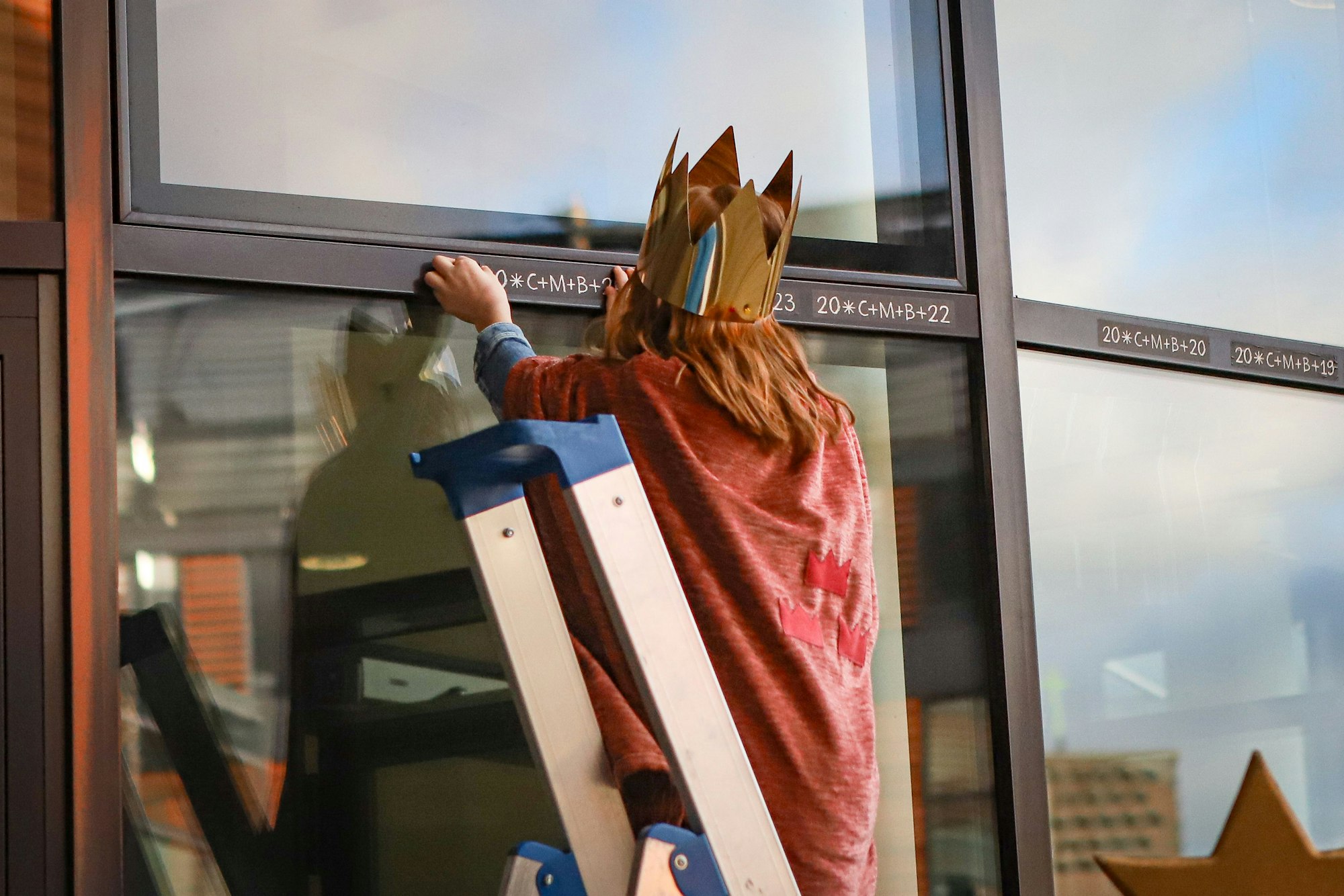 Eine Sternensängerin befestigt das diesjährige Kreidezeichen „20+C+M+B+24“ über der Eingangstür des Leverkusener Rathauses.