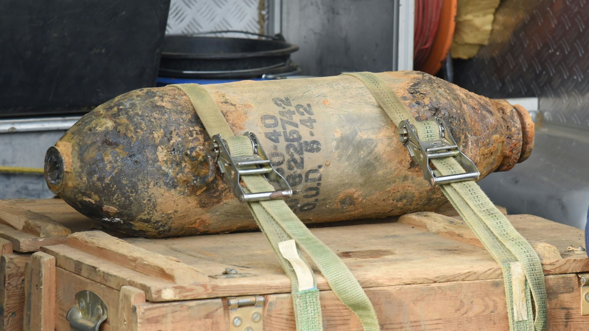 Eine entschärfte Fliegerbombe liegt auf einer Holzkiste und ist mit Gurten gegen Verrutschen gesichert.
