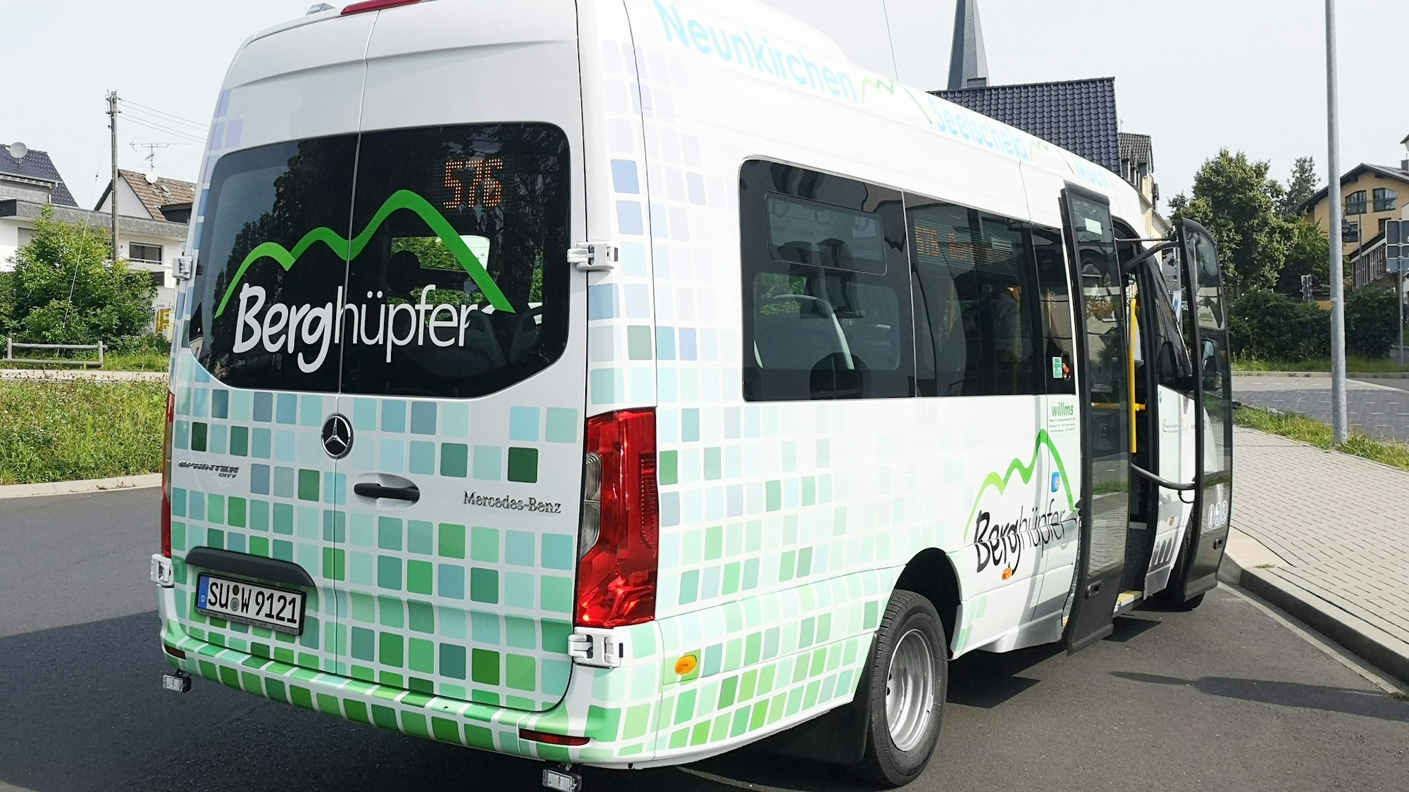 Ein Kleinbus mit der Aufschrift „Berghüpfer“ in den Farben grün und weiß.