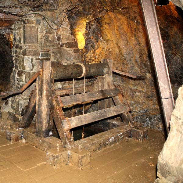 Der Tunnel eines ehemaligen Erzbergwerks mit steinernen Wänden und Stahlstreben.