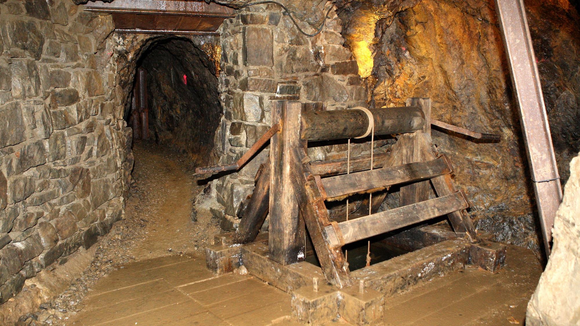 Der Tunnel eines ehemaligen Erzbergwerks mit steinernen Wänden und Stahlstreben.