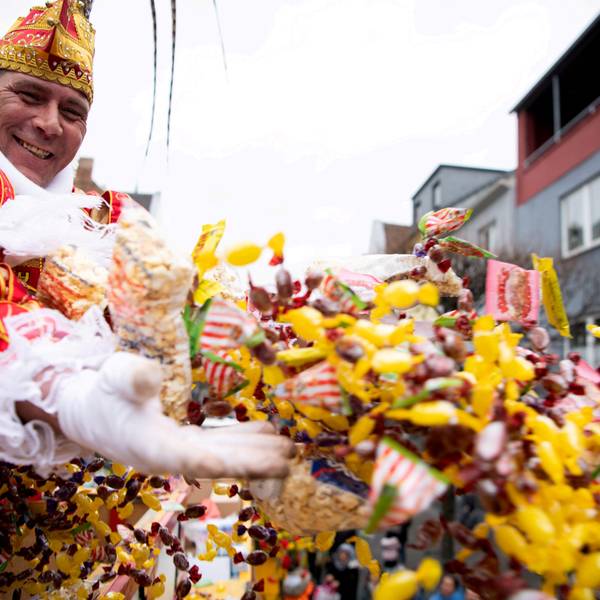 Das Bild zeigt eine Tollität, wie sie mit beiden Händen eine große Anzahl an Kamelle wirft.