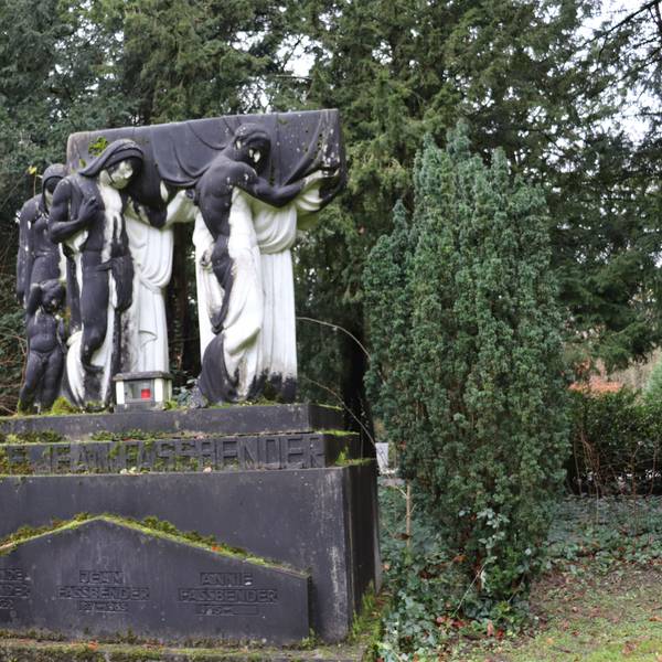 Vier weiße lebensgroße Marmorfiguren, stehn auf einem Sockel und tragen einen Sarg