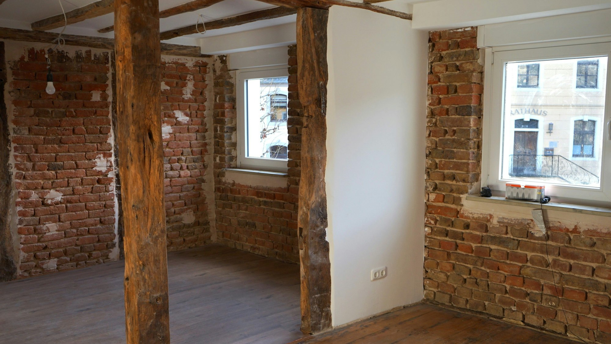 Ein Raum mit freigelegten Backsteinwänden und Holzbalken.