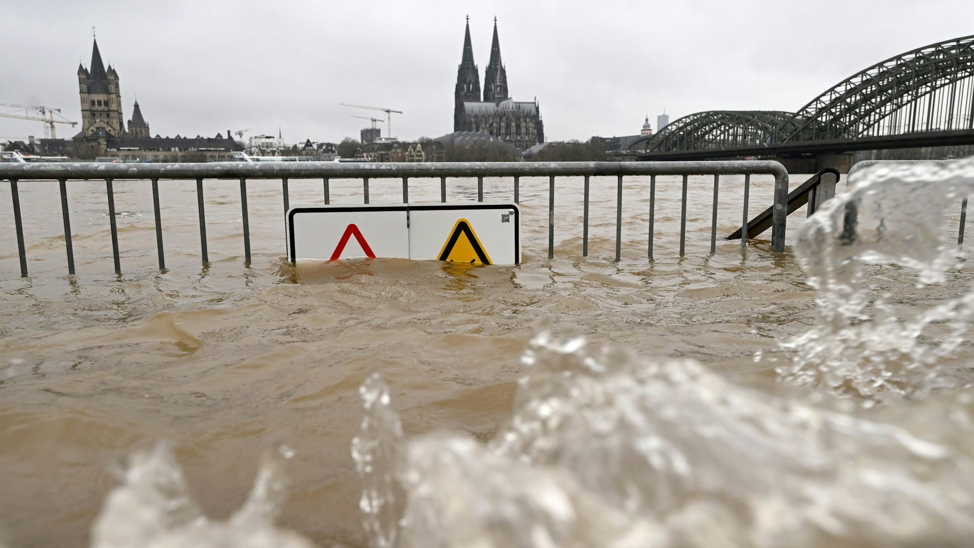 06.01.2024, Nordrhein-Westfalen, Köln: Blick auf den Hochwasser führenden Rhein vor dem Dom und der Hohenzollernbrücke. Der Pegel soll am Samstag die kritische Marke übersteigen. Gegen Abend soll der höchste Stand erreicht sein. Foto: Roberto Pfeil/dpa +++ dpa-Bildfunk +++