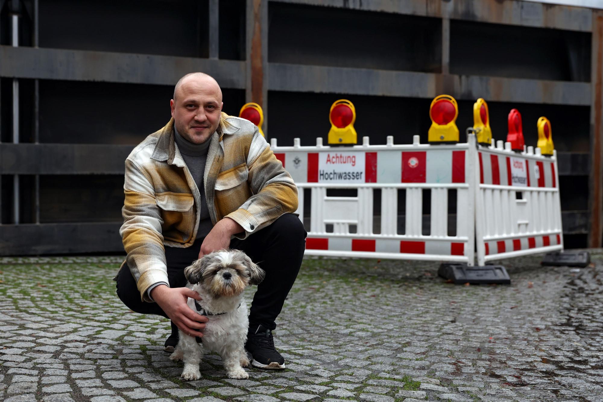 Ein Mann und ein kleiner Hund vor einer Absperrung