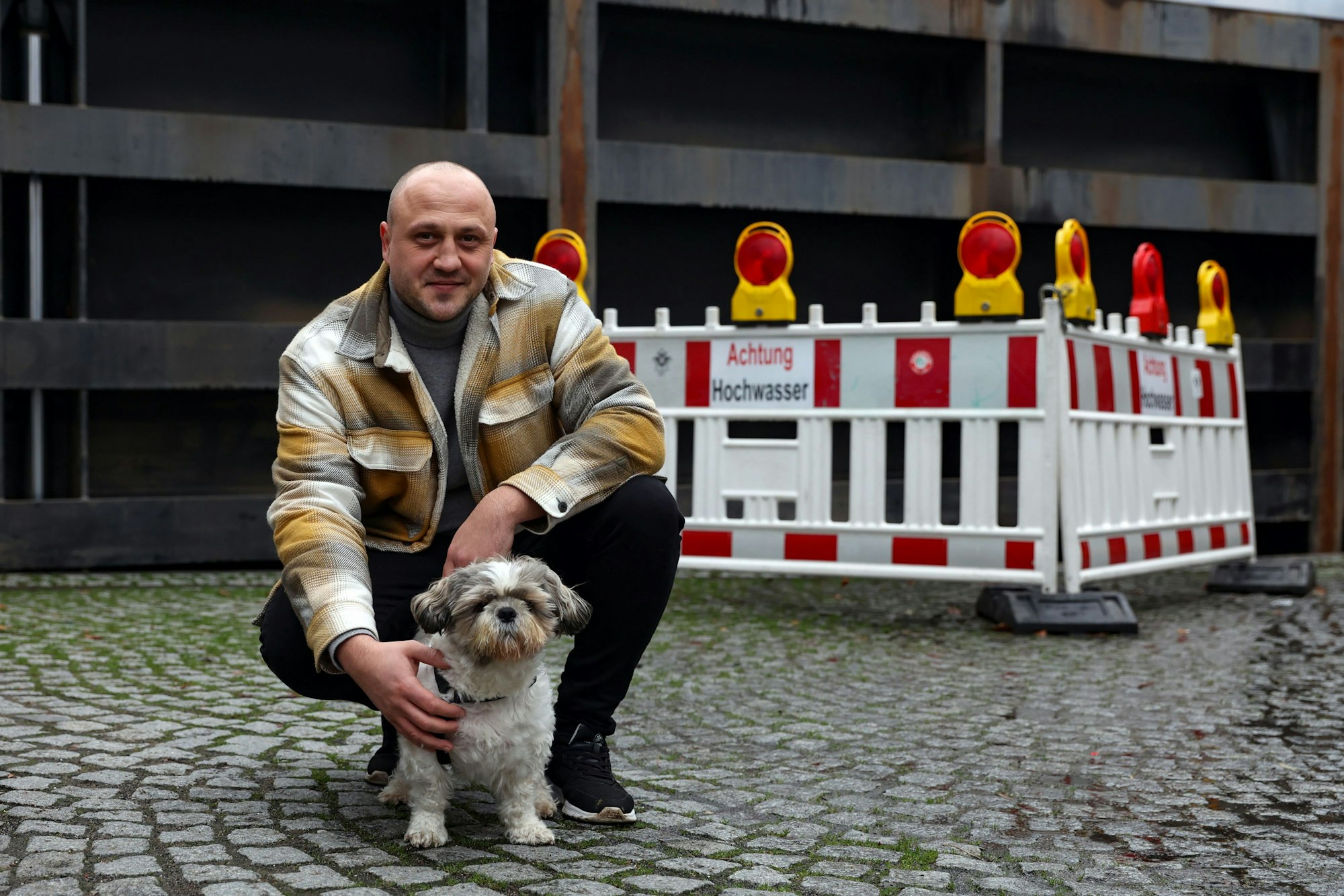 Ein Mann und ein kleiner Hund vor einer Absperrung