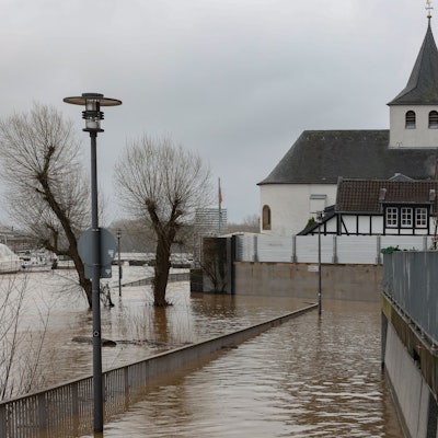 Die Promenade in Köln Rodenkirchen ist vom Hochwasser überflutet. Gehwege sind nicht mehr betretbar und Bäume ragen aus dem Wasser.