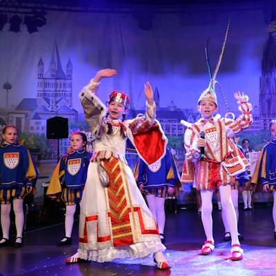 Drei Kinder im Ornat auf der Bühne.