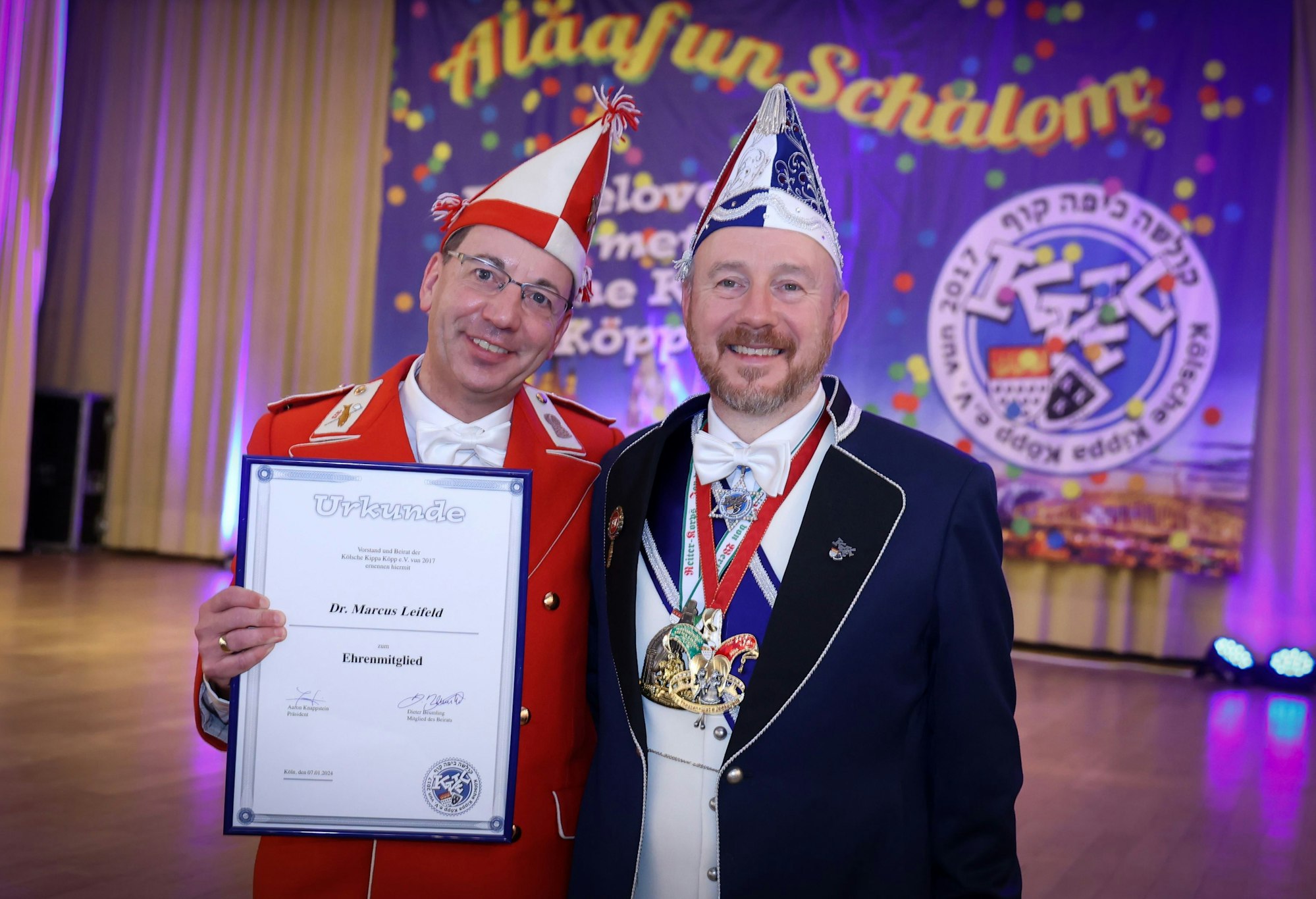 Ehrenmitglied Marcus Leifeld (links) mit Urkunde und Aaron Knappstein vor einem Plakat der Kippa Köpp.