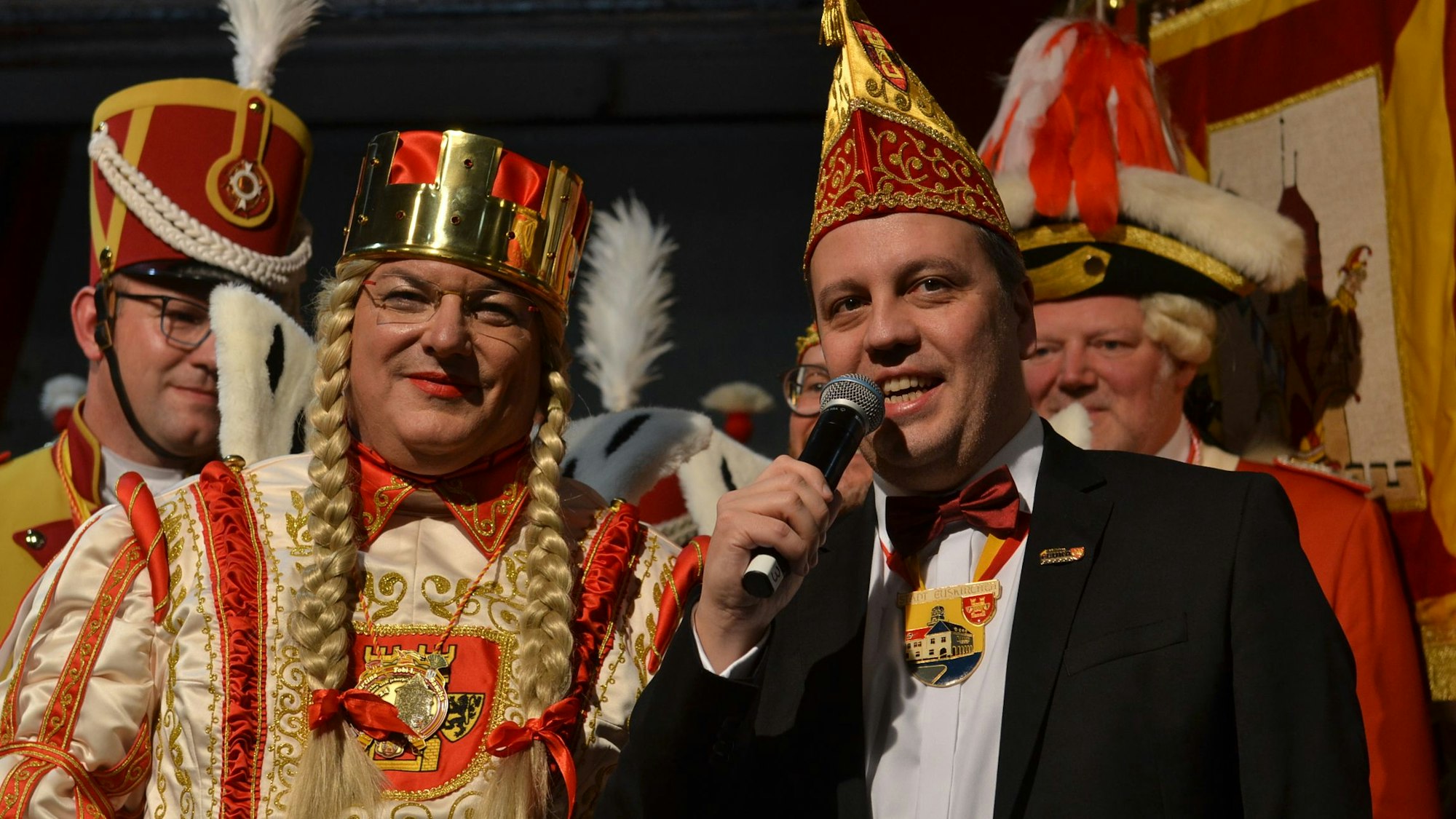 Bürgermeister Sacha Reichelt hält ein Mikrofon in der Hand, neben ihm steht Jungfrau Martina (Martin Niessen)
