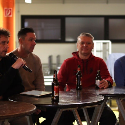 Moderator Tom Steinicke hält das Mikrofon in der Hand, neben ihm sitzen Uwe Metternich, Guido Mertens und Fabian Ewertz.