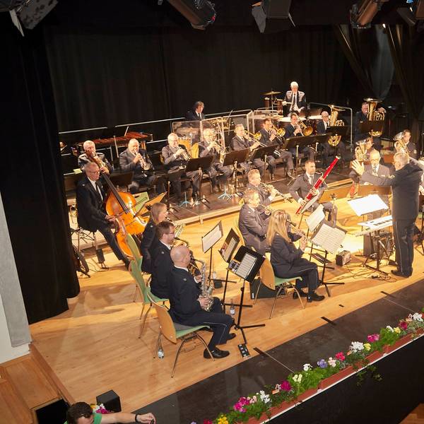 Das Landespolizeiorchester auf der Bühne im Gemünder Kursaal, die mit Blumen dekoriert ist.