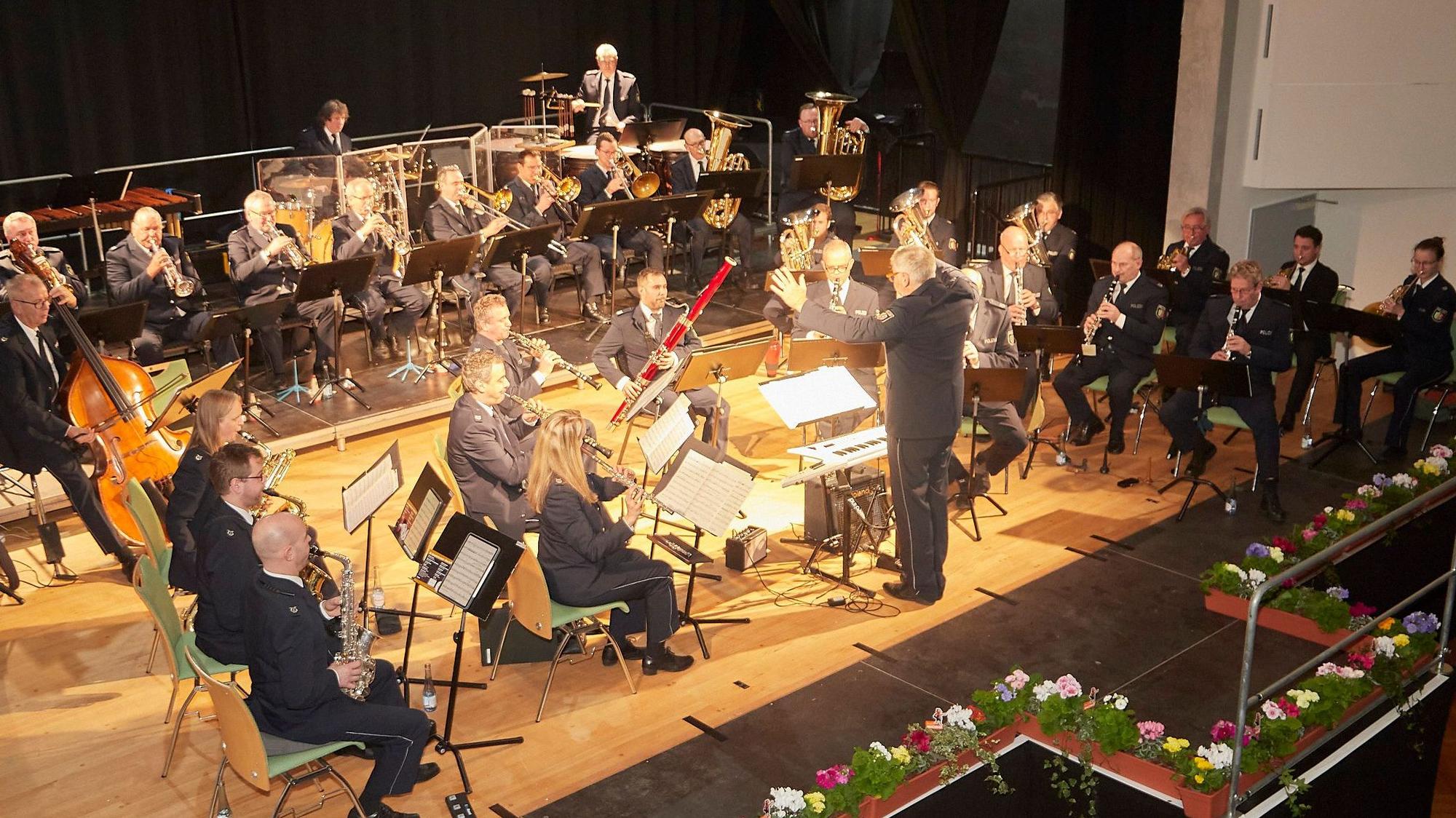 Das Landespolizeiorchester auf der Bühne im Gemünder Kursaal, die mit Blumen dekoriert ist.