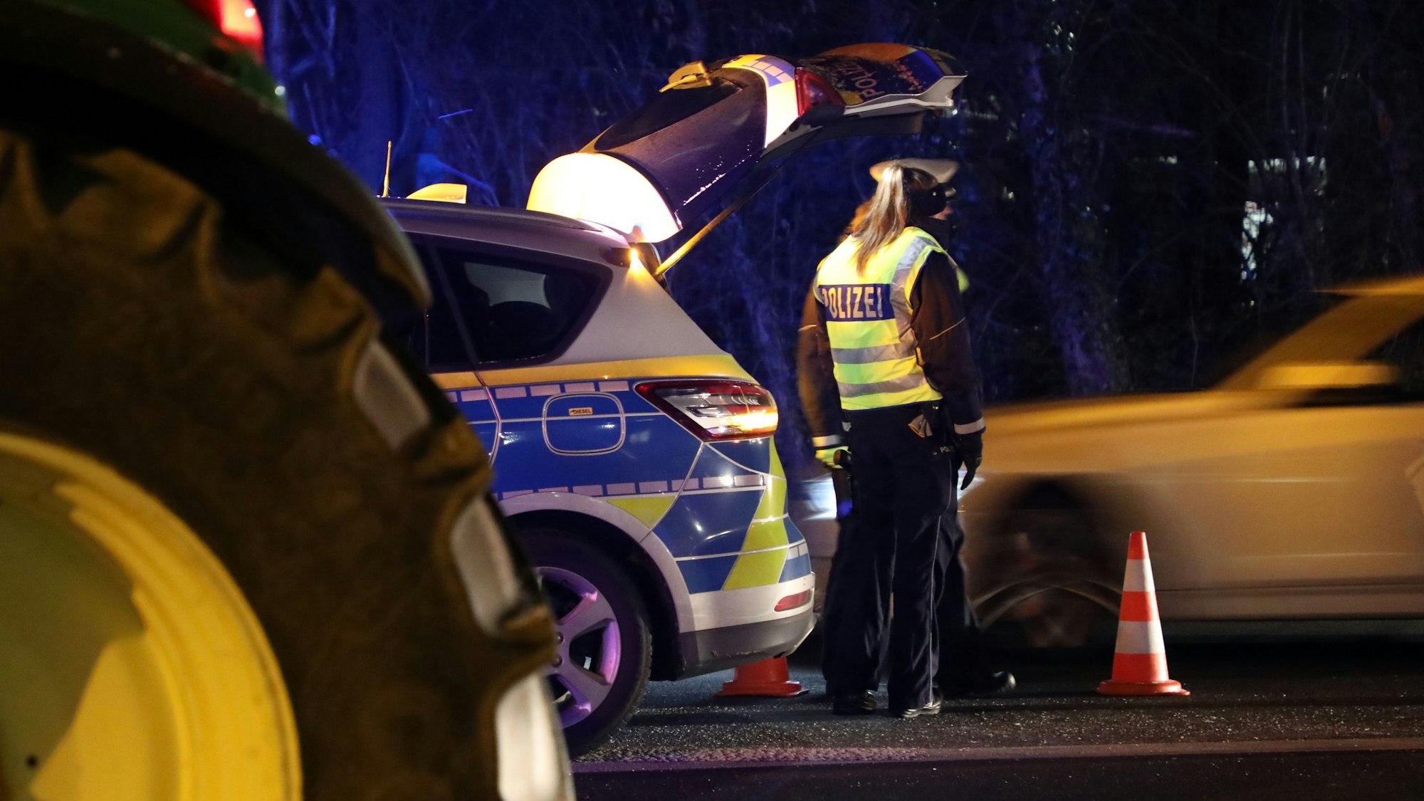 Eine Polizistin und ein Polizist regeln in Overath in der Nacht den Verkehr.