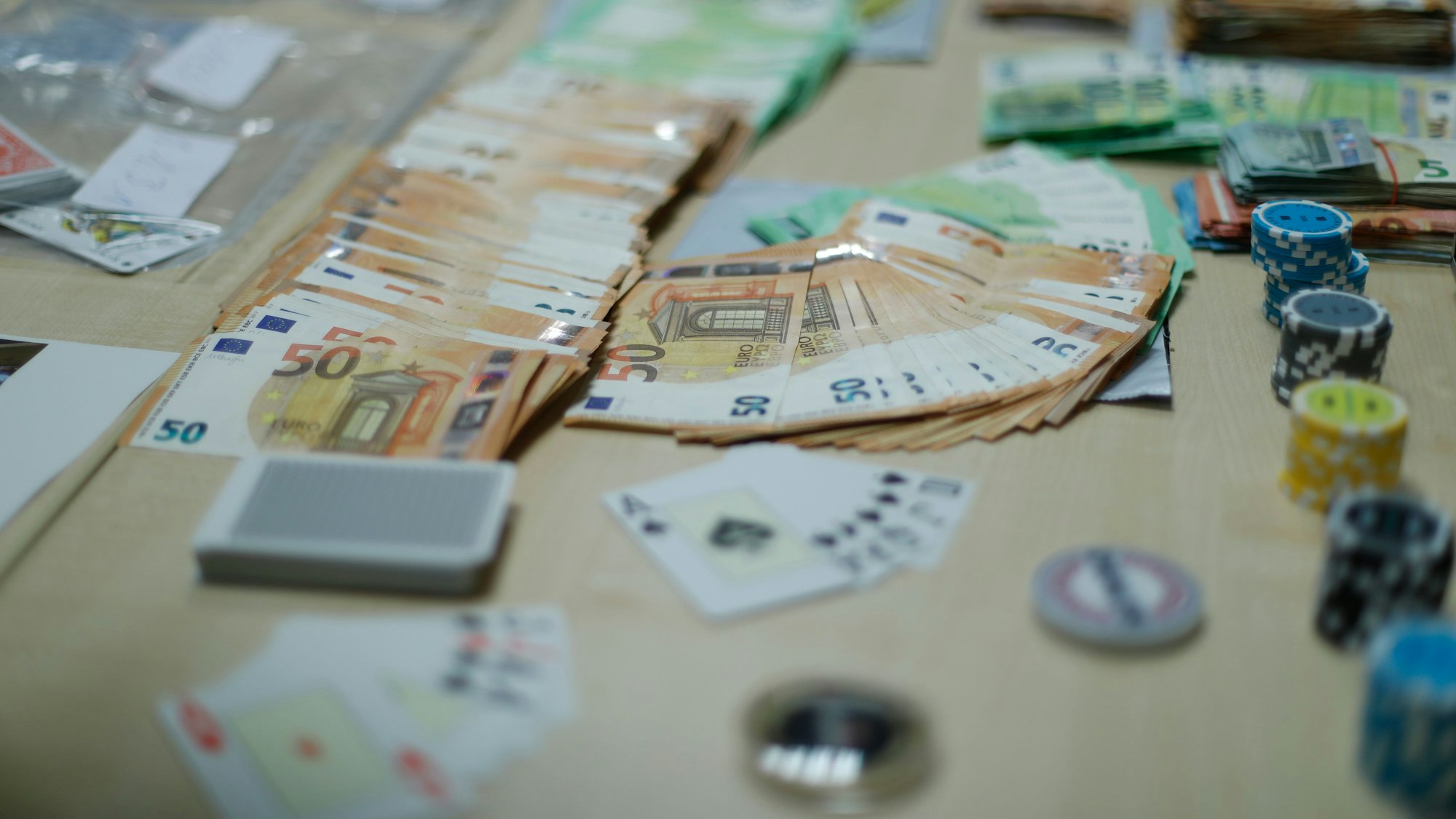 Das Foto zeigt einen Tisch mit Spielkarten und hohen Geldbeträgen.