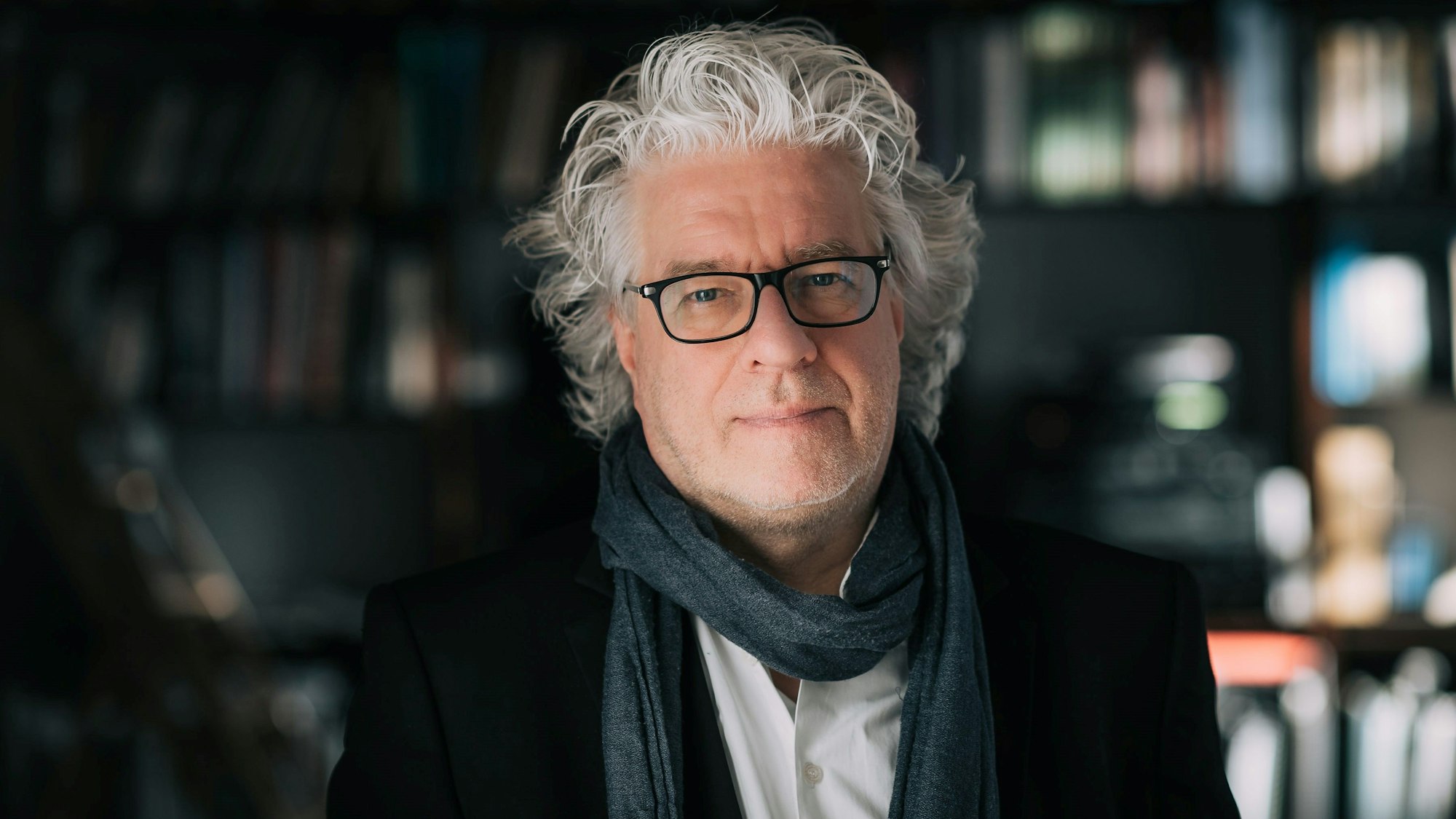 Christoph Spering steht vor einer Bücherwand.