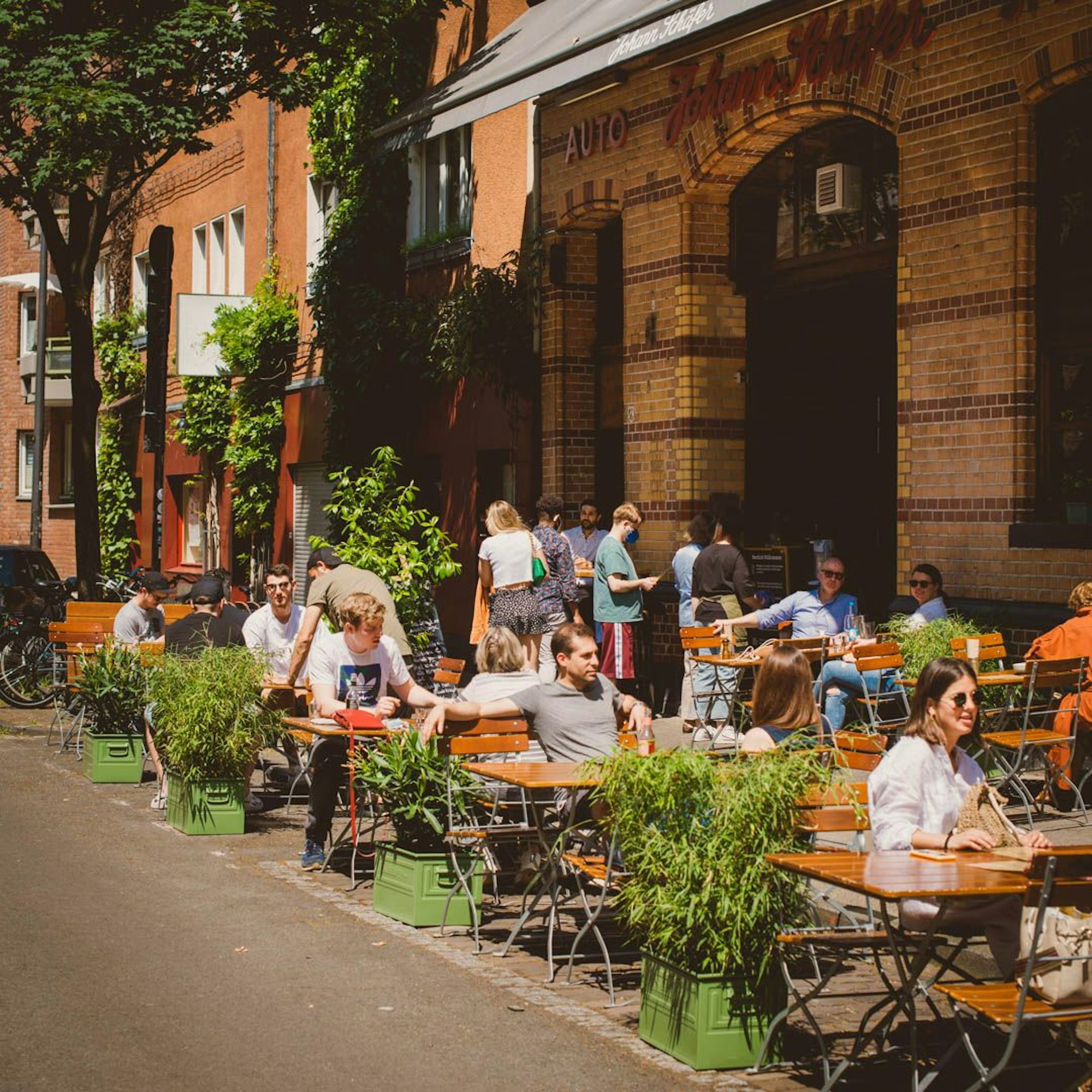 Menschen sitzen draußen vor dem Brauhaus Johann Schäfer.