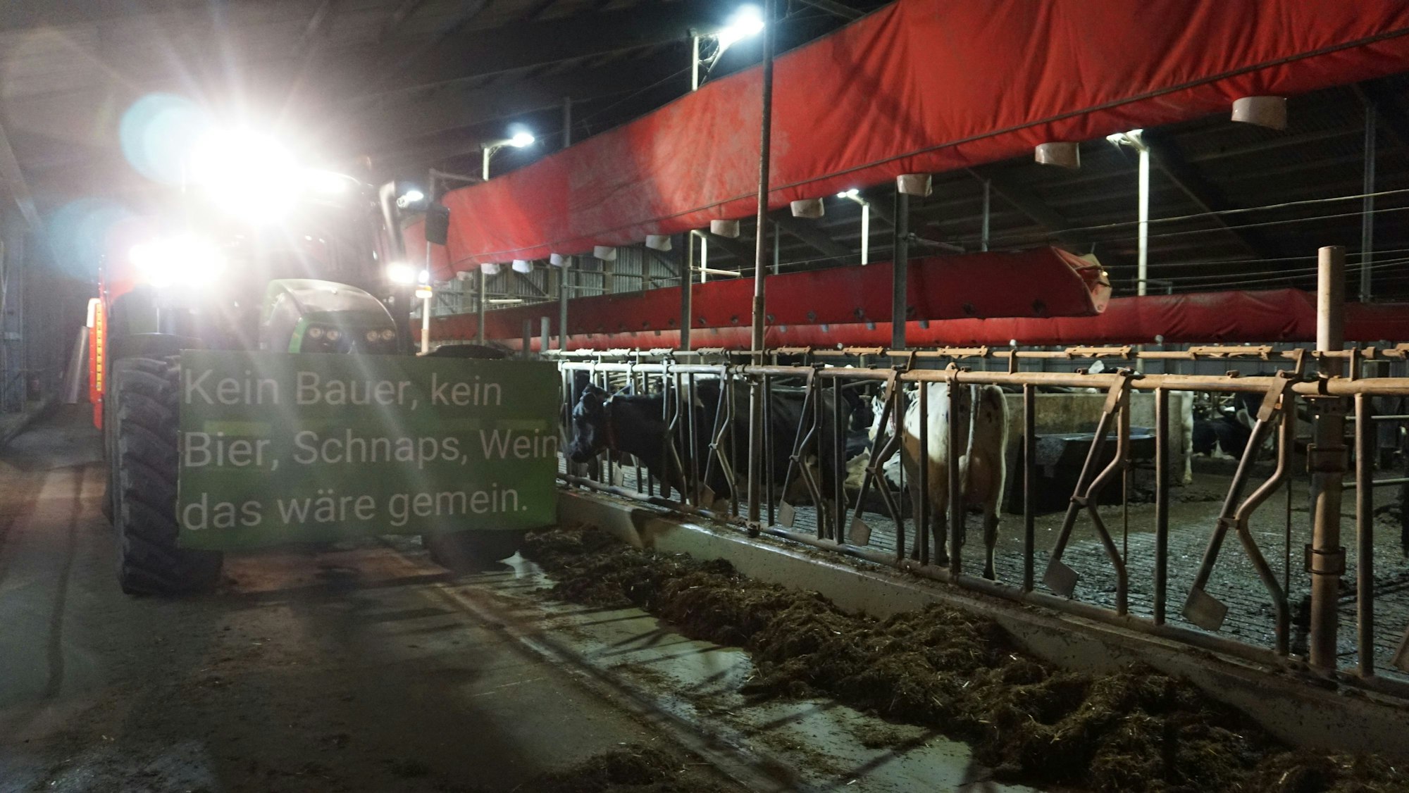 Ein Trecker ist mit einem Banner versehen. Auf dem Schild steht: "Kein Bauer, kein Schnaps, Wein, das wäre gemein.