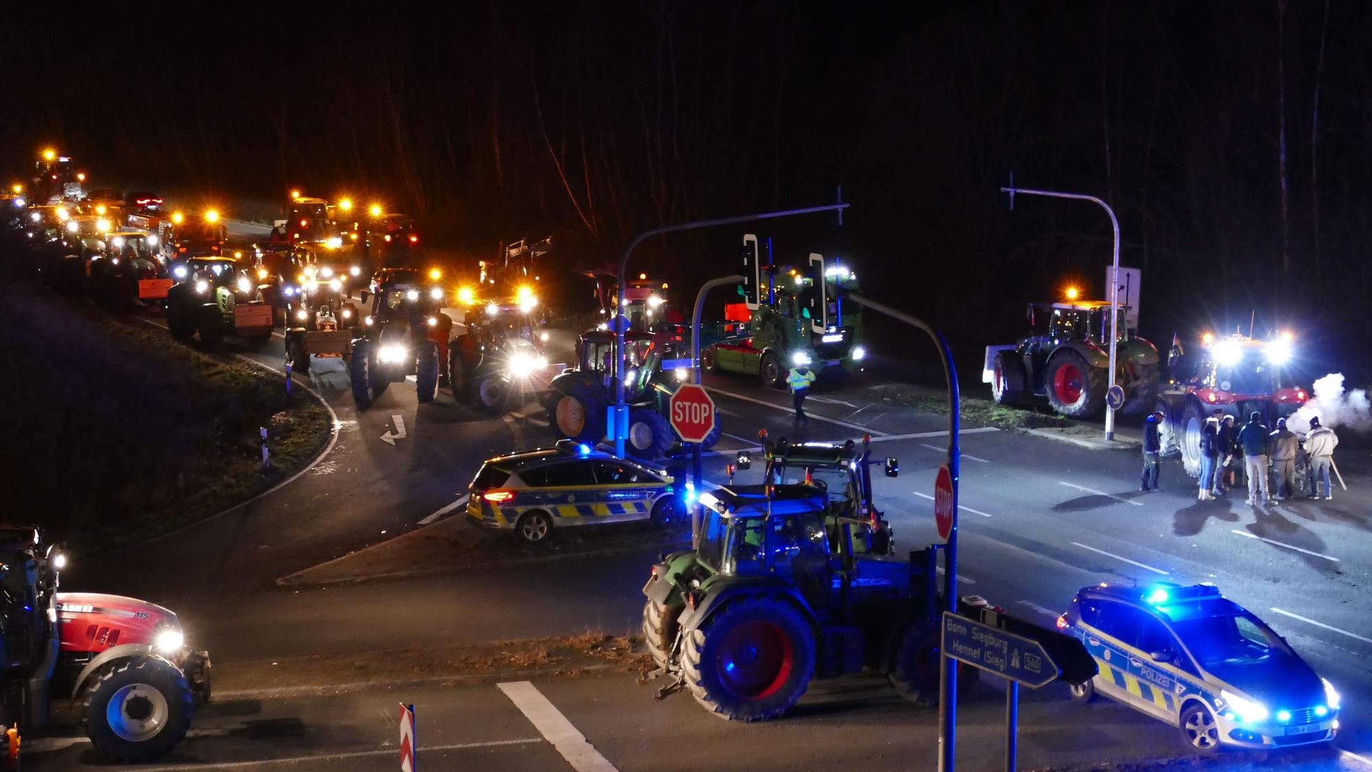 Zahlreiche Traktoren stehen auf einer Straße.