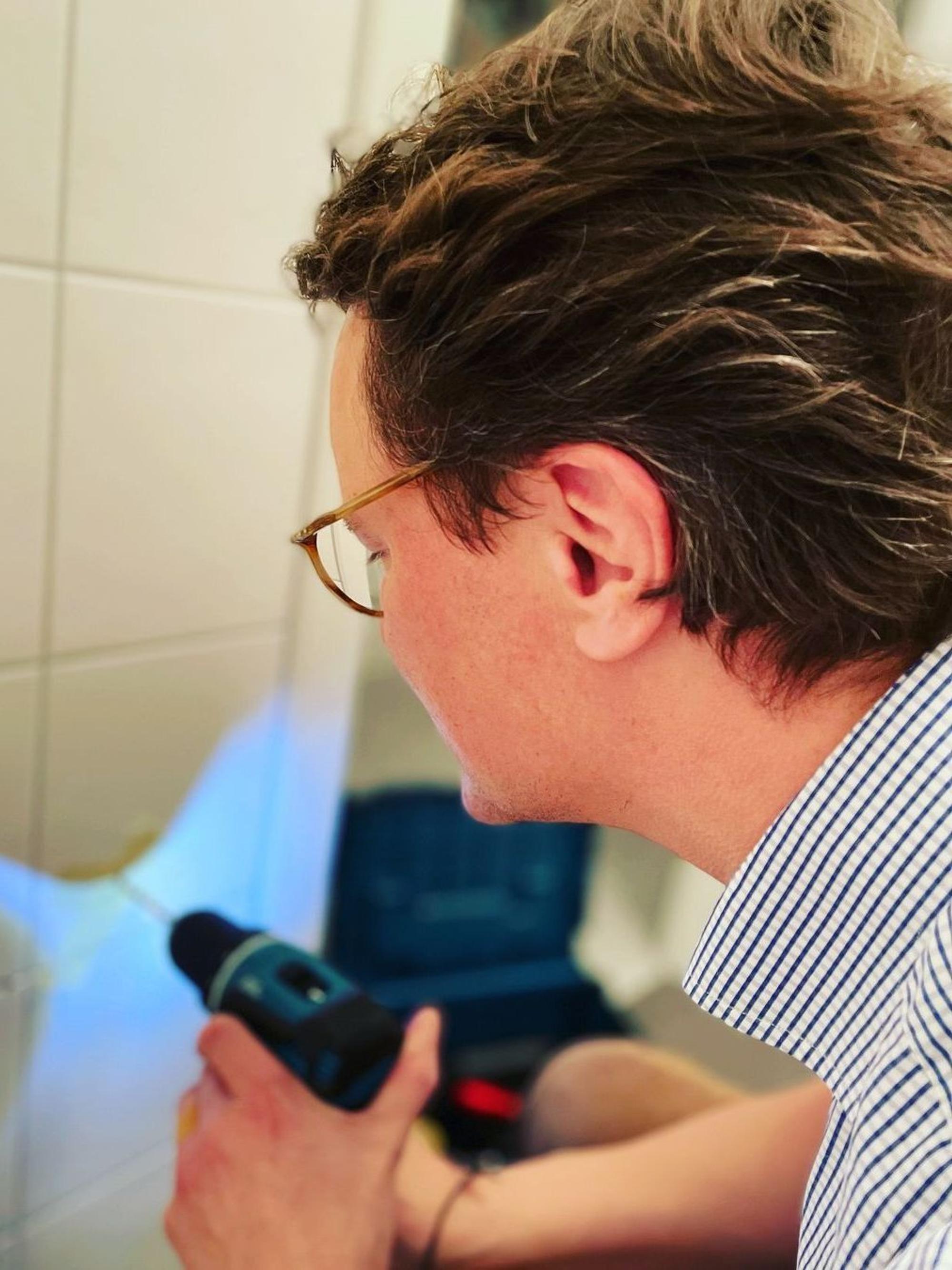 Hendrik Wüst bohrt in eine Kachel.