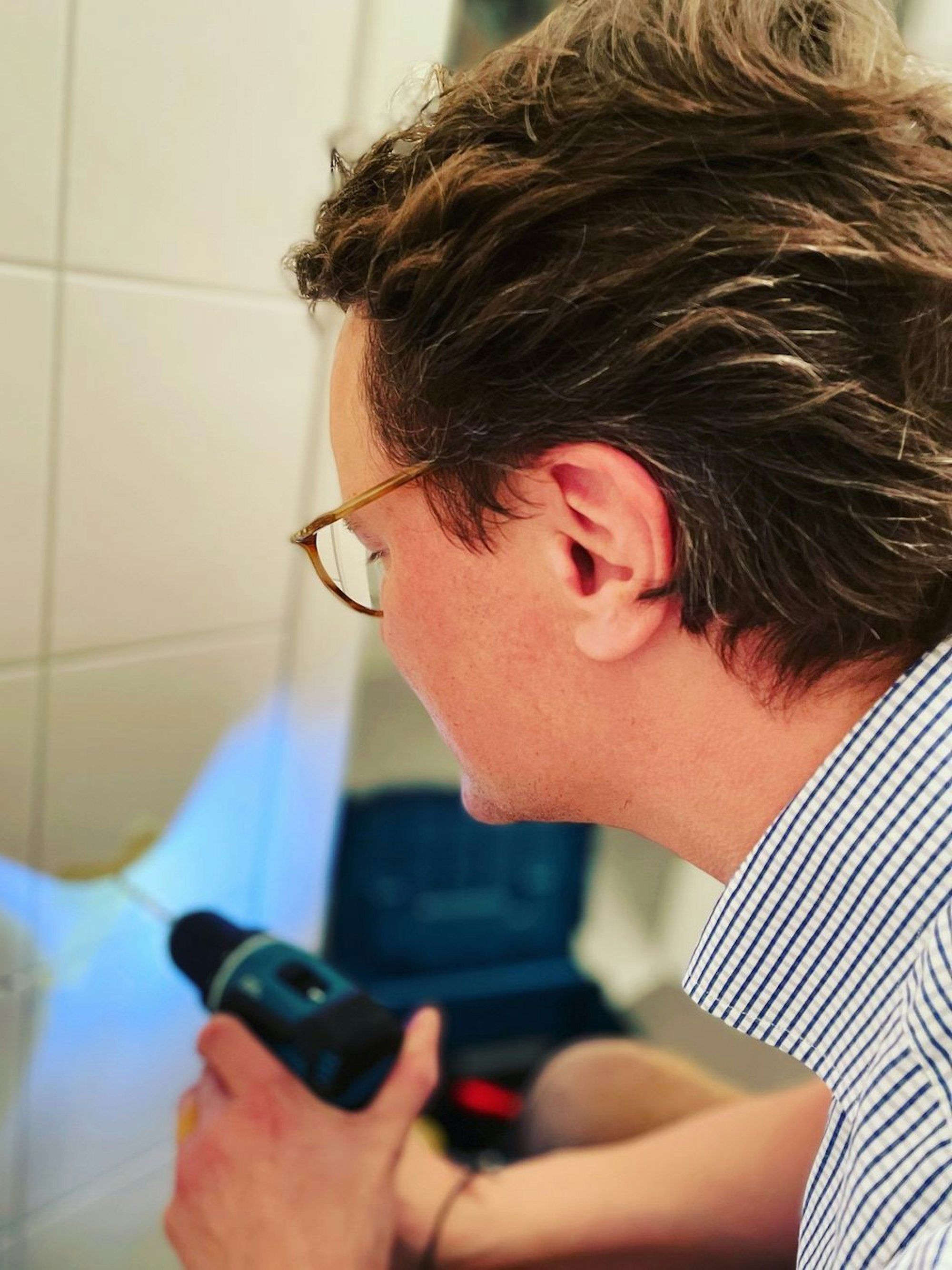 Hendrik Wüst bohrt in eine Kachel.