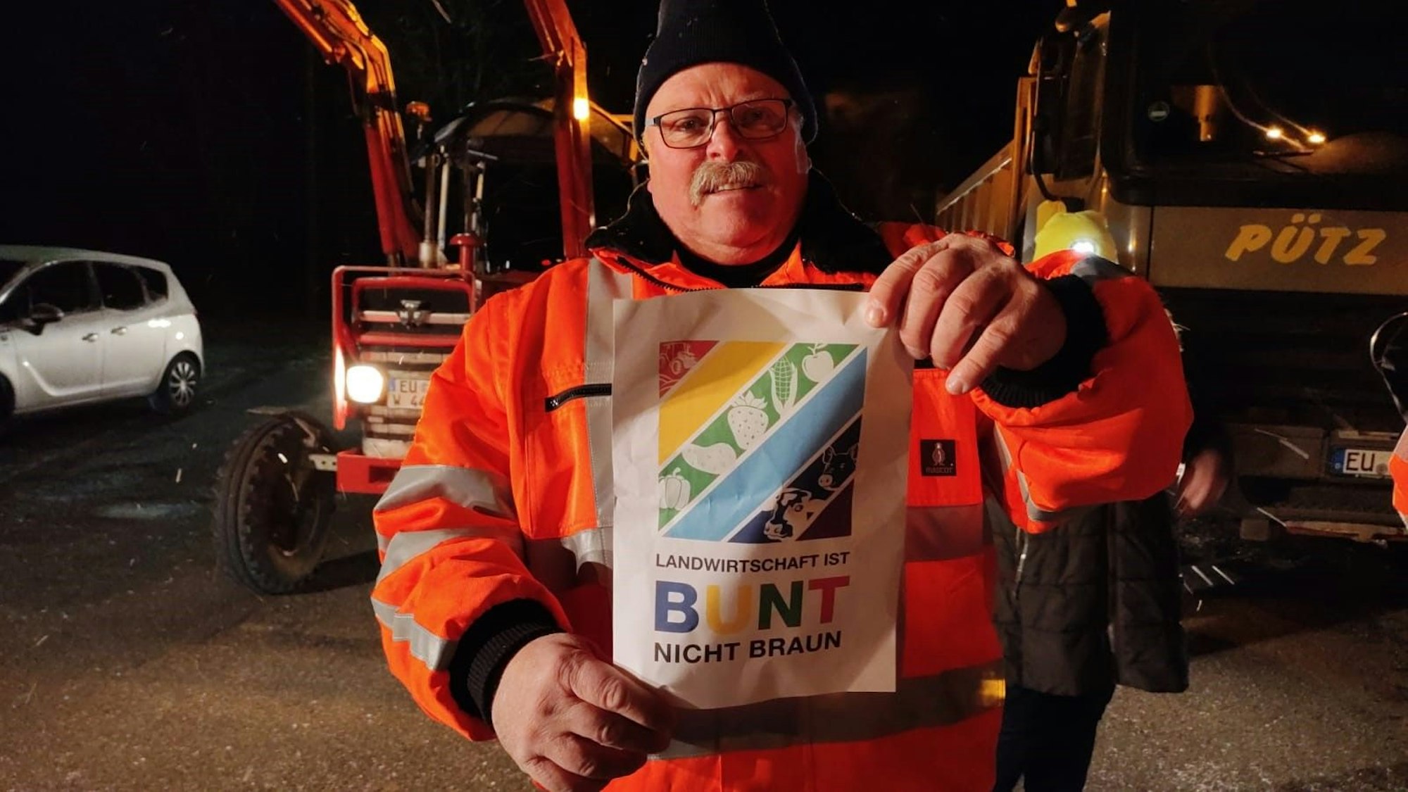 Im Mühlenpark setzen Landwirte und Bürger ein Zeichen: Landwirtschaft ist bunt, nicht braun. Das entsprechende Plakat zeigt Karl-Josef Schmitz. Es ist auch in zahlreichen Autos zu sehen.