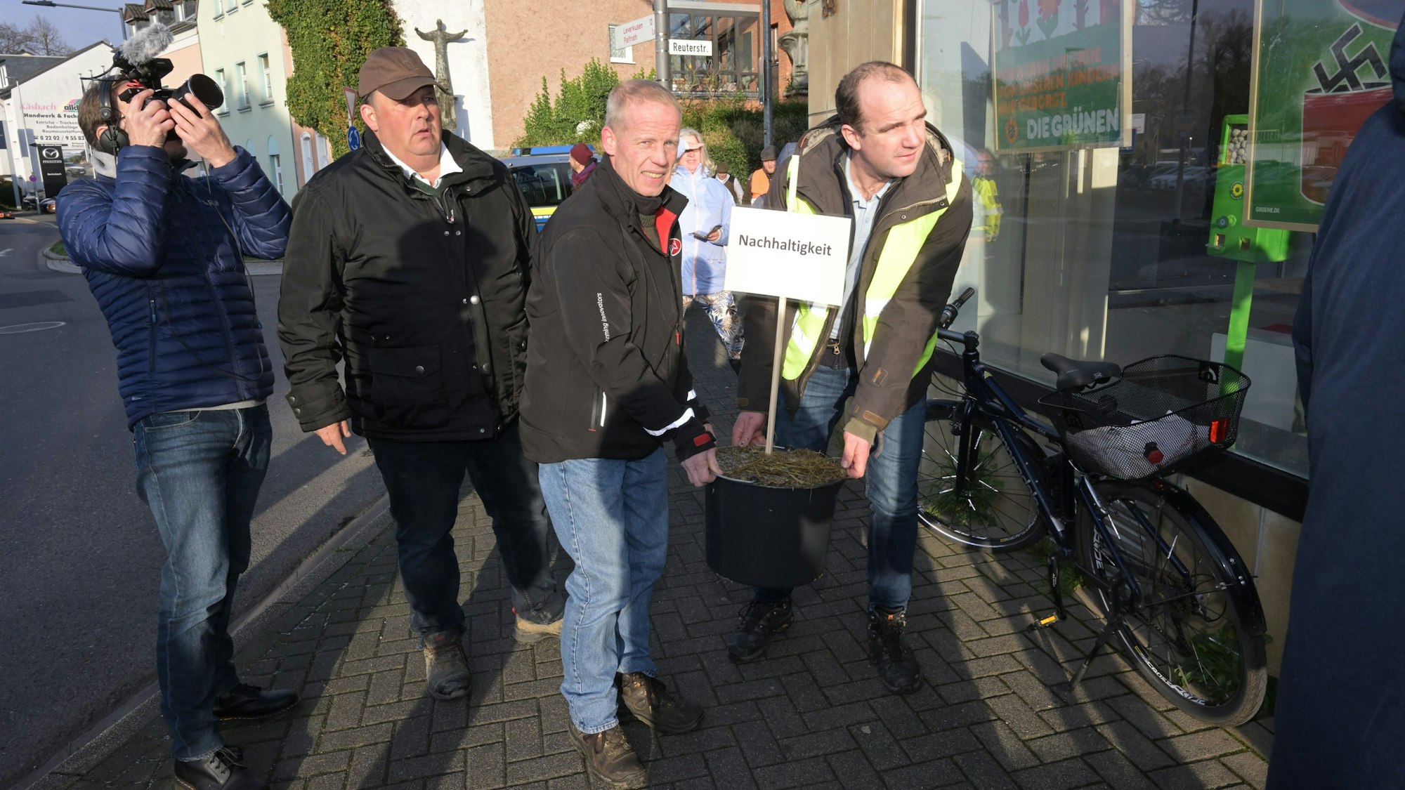 Einen Eimer mit Mist tragen Landwirte in die Kreisgeschäftsstelle der Grünen in Bergisch Gladbach.