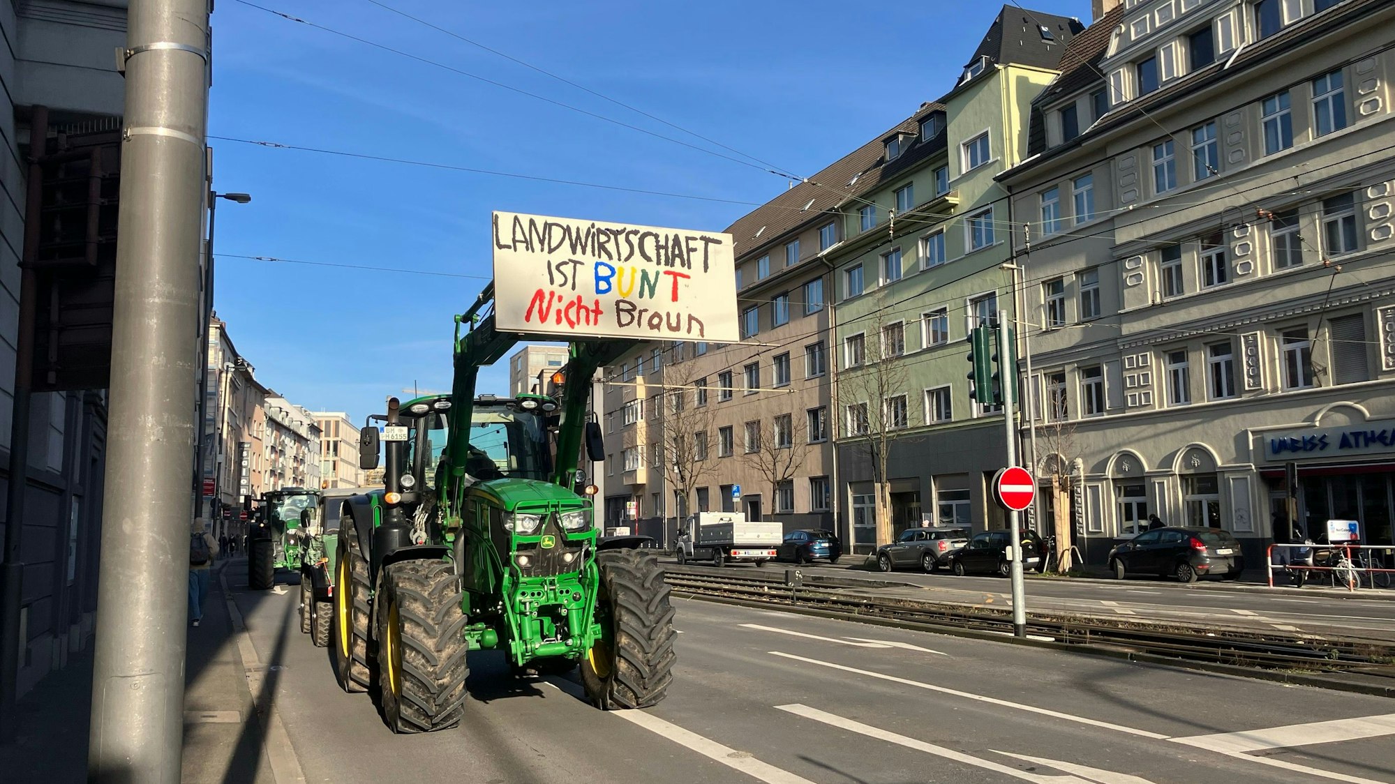 Hunderte Landwirte ziehen in einem langen Protestzug am 8. Januar durch Köln. Hier auf der Justinianstraße in Köln-Deutz. Dieser Traktorfahrer positioniert sich gegen Rechts mit seinem Plakat: "Landwirtschaft ist bunt nicht braun"