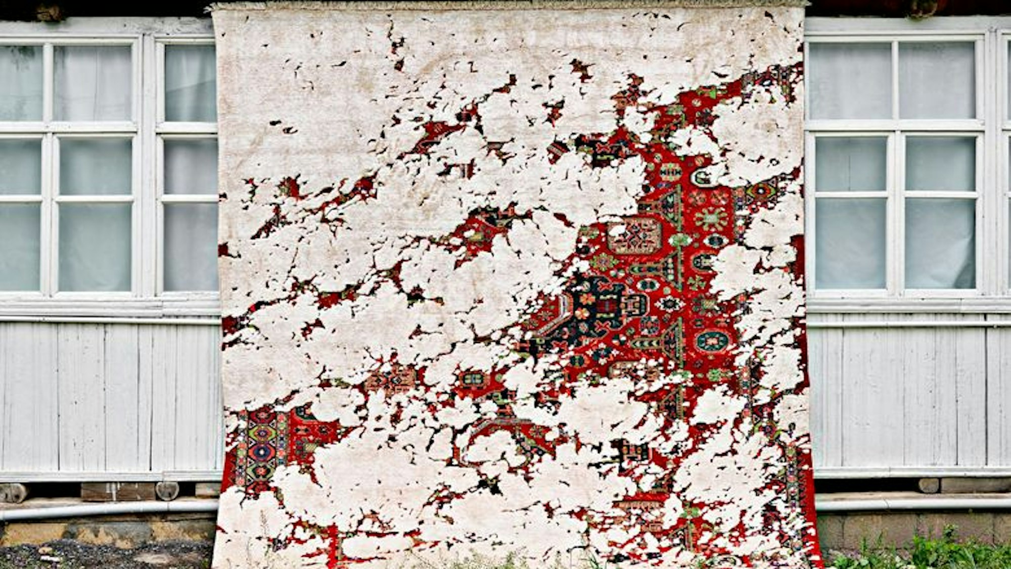 Ein Teppich an einer Hauswand drapiert.