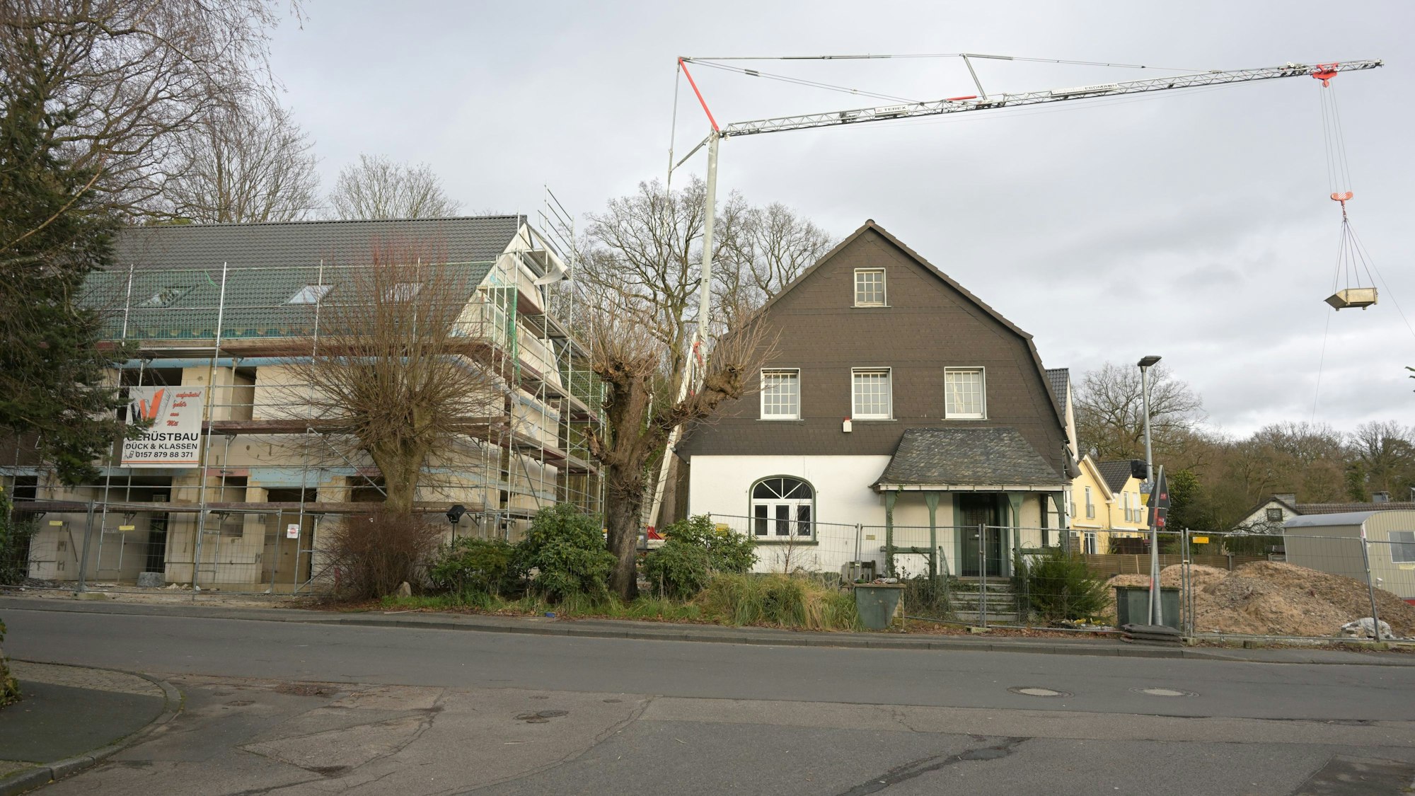 Rechts steht der Altbau, links daneben der Rohbau mit für ein Doppelhaus mit Gerüst.