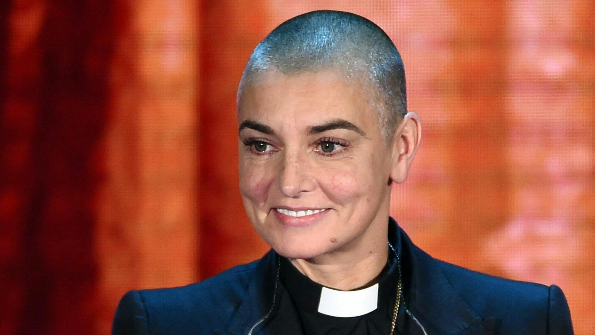 Sinéad O'Connor lächelt in die Kamera.