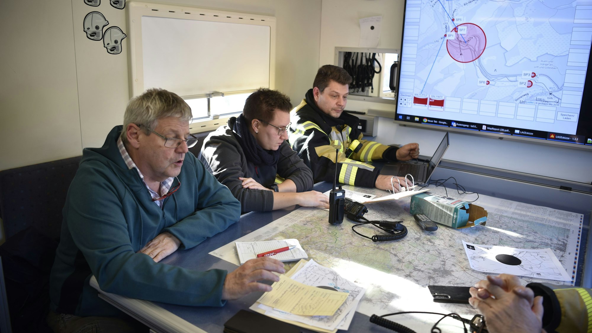 Drei Mitglieder der Einsatzleitung bei einer Besprechung vor der Bombensprengung.