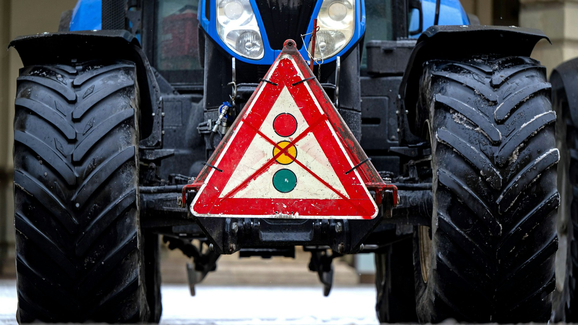 Ein durchgestrichenes Verkehrsschild mit einer Ampel hängt während einer Demonstration von Landwirten an einem Traktor.