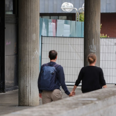 Eine Person schläft vor dem Römisch-Germanischen Museum in einem Schlafsack neben einem Einkaufswagen.