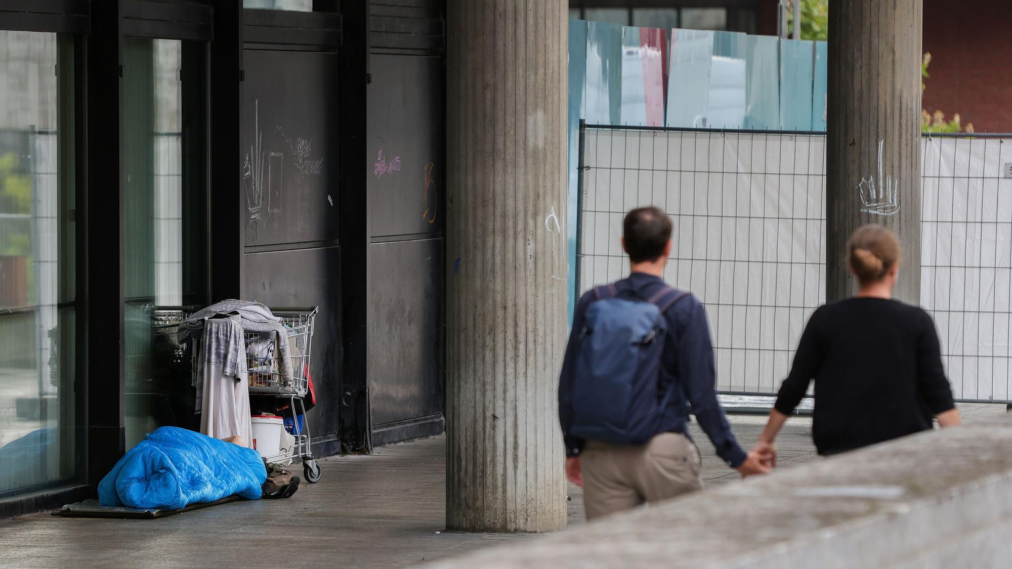 Eine Person schläft vor dem Römisch-Germanischen Museum in einem Schlafsack neben einem Einkaufswagen.