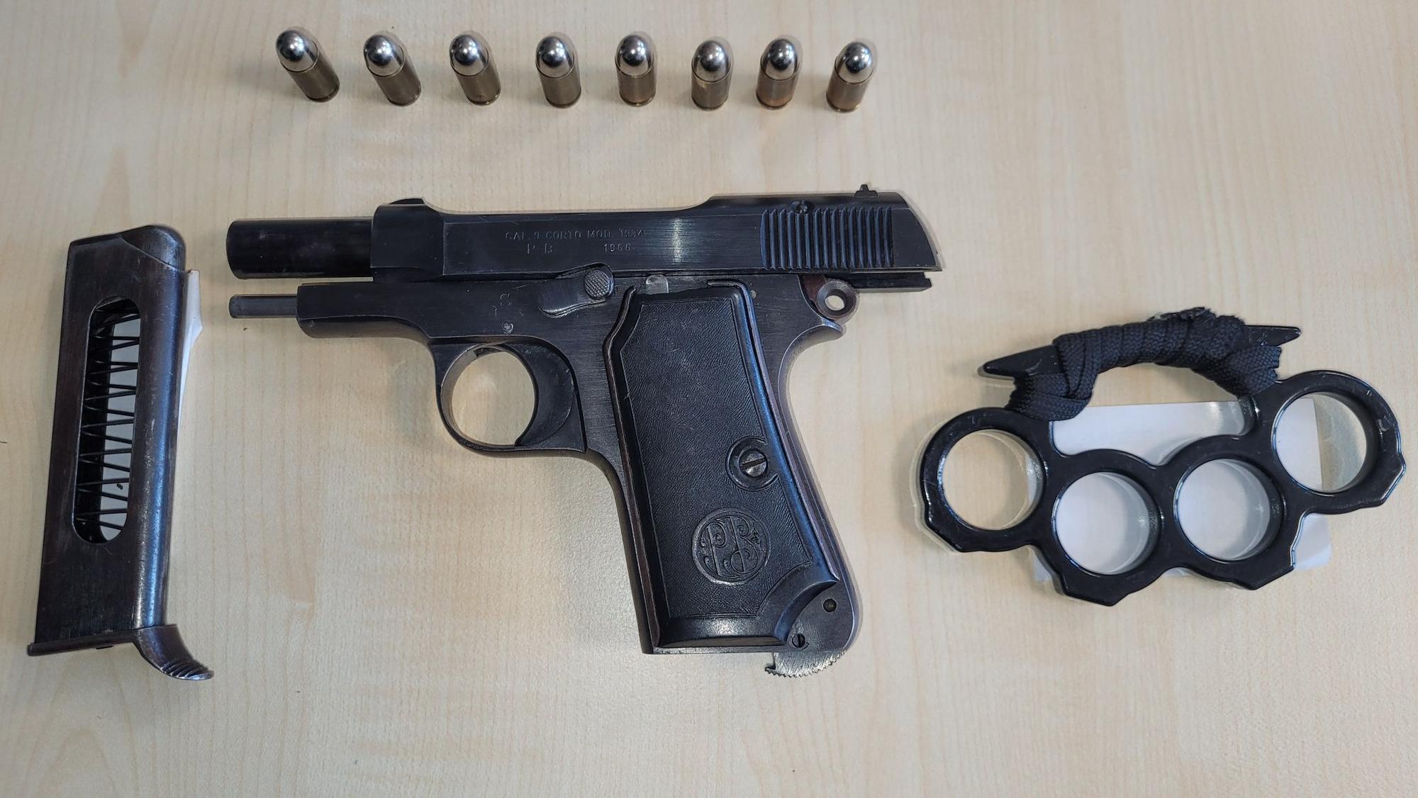 Eine Schusswaffe, ein passendes Magazin und acht Patronen liegen neben einem Schlagring auf einem Tisch.